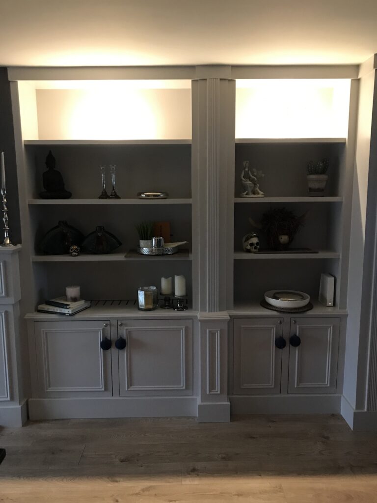 A white classic-style built-in shelving unit with decorative items.